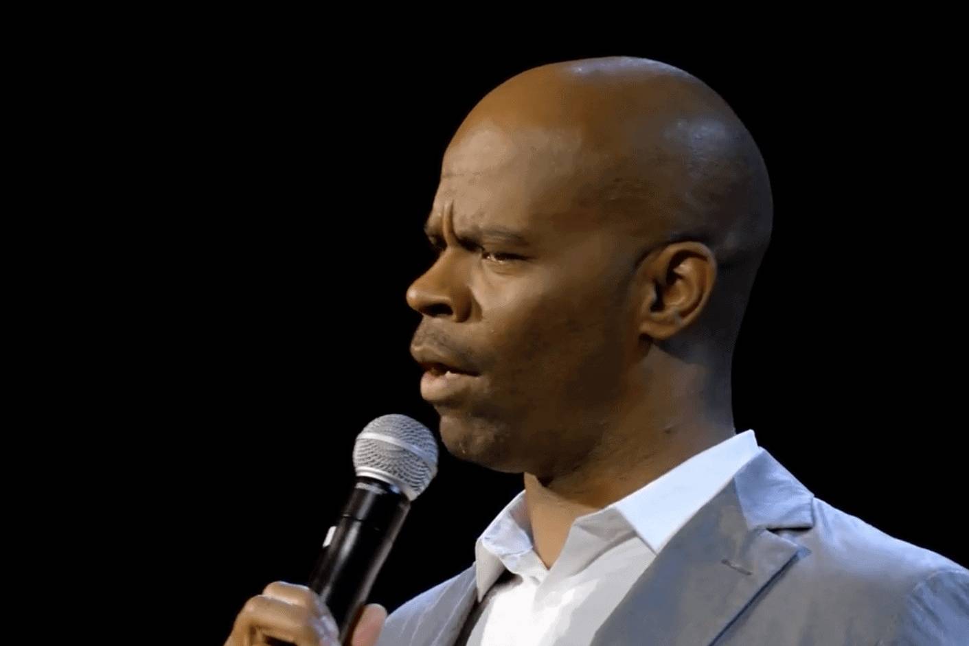 Rich black man speaking into microphone during presentation or conference.