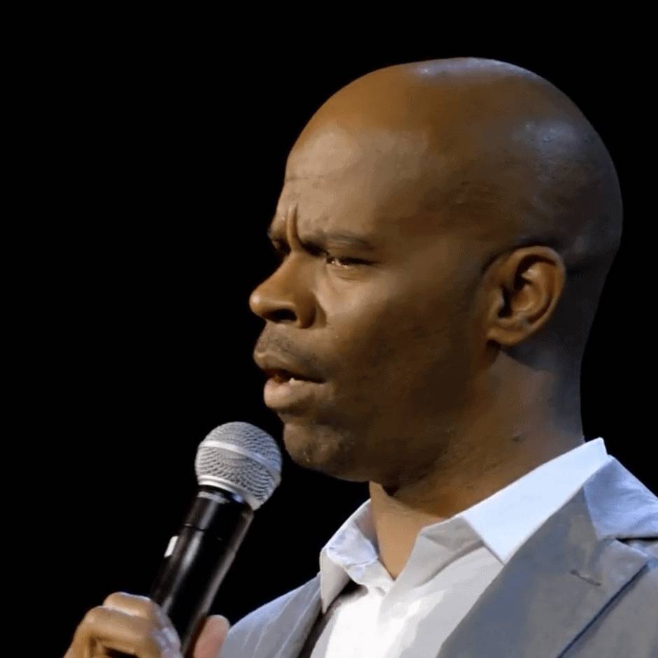 Rich black man speaking into microphone during presentation or conference.