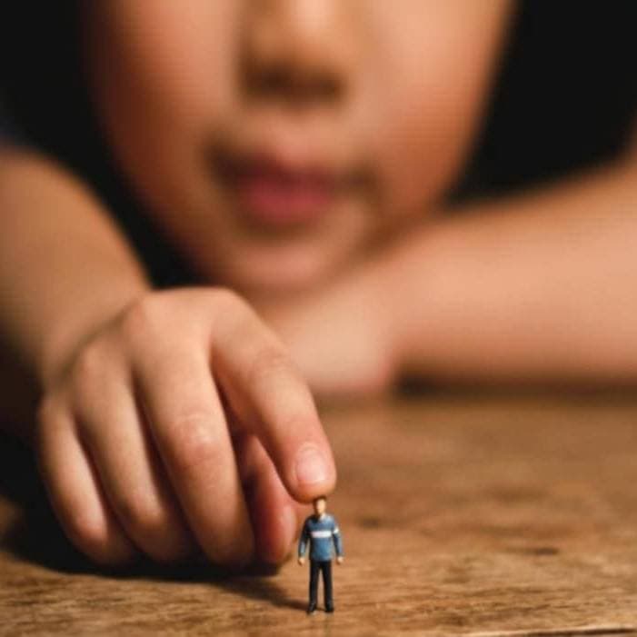 Child holding a tiny figurine, symbolizing strength and perspective.