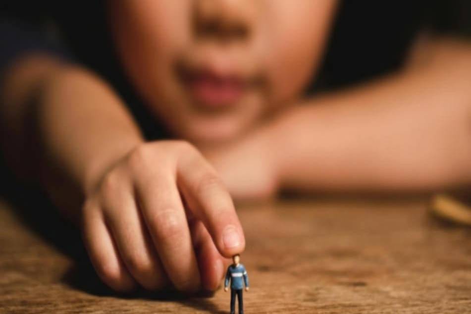 Child holding a tiny figurine, symbolizing strength and perspective.