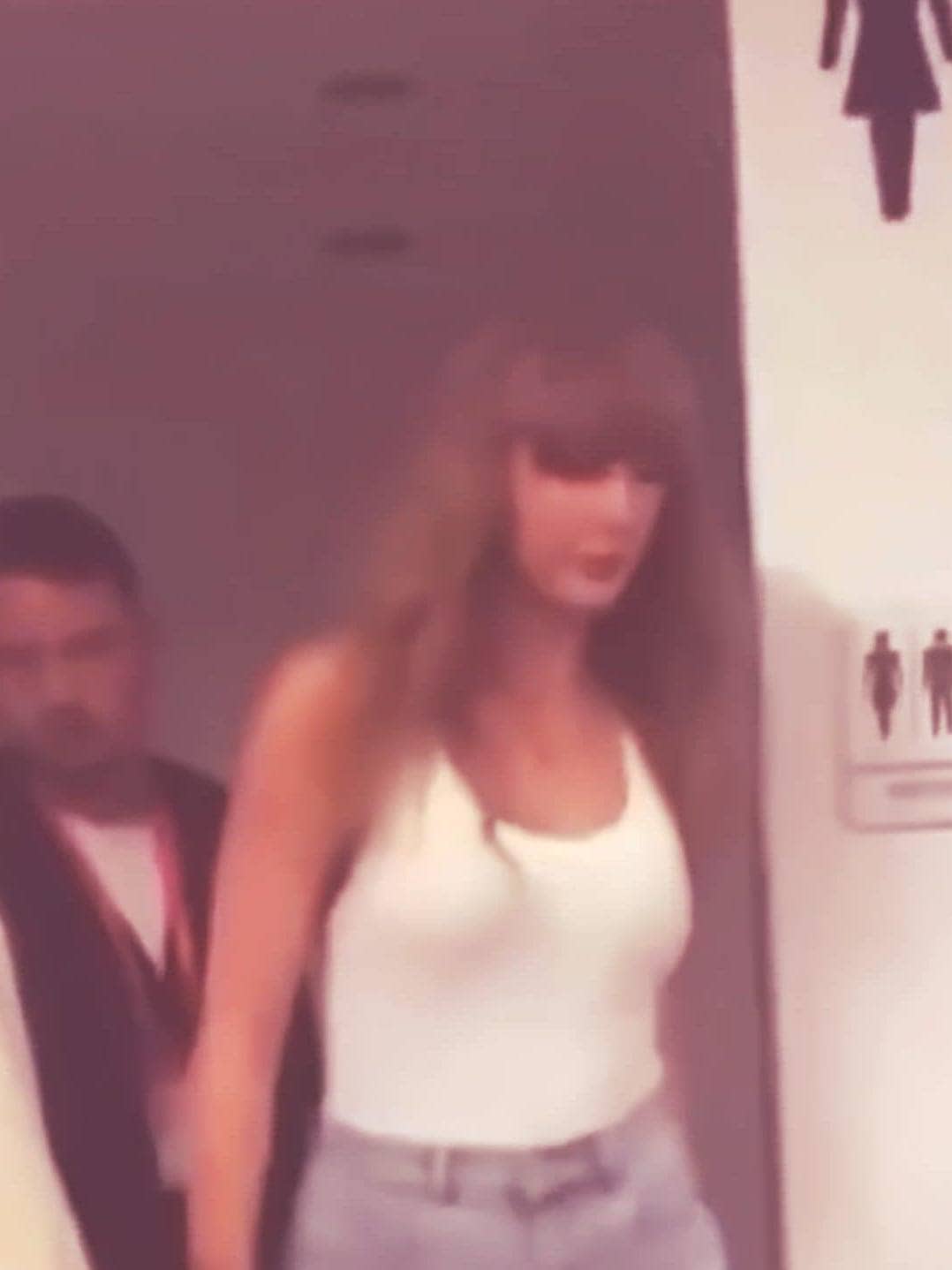 Leaving restroom with bodyguard, Taylor Swift exiting public restroom.
