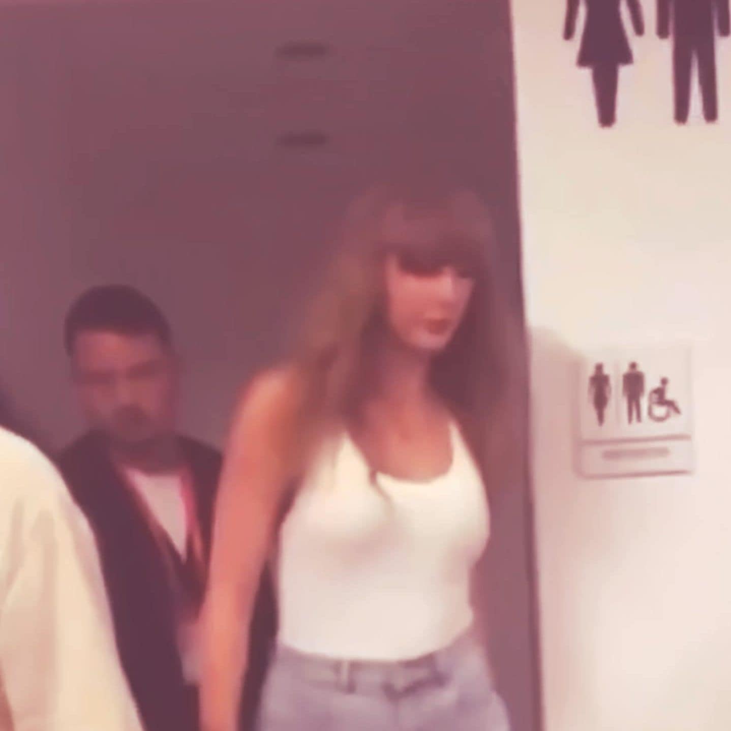 Leaving restroom with bodyguard, Taylor Swift exiting public restroom.