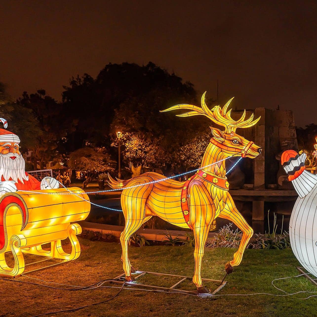 Colorful Christmas decorations including Santa, reindeer, and snowman at night.