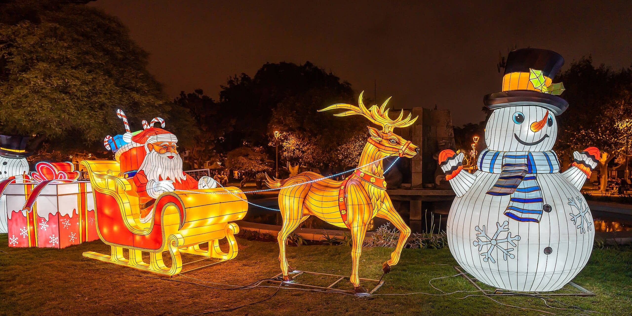 Colorful Christmas decorations including Santa, reindeer, and snowman at night.