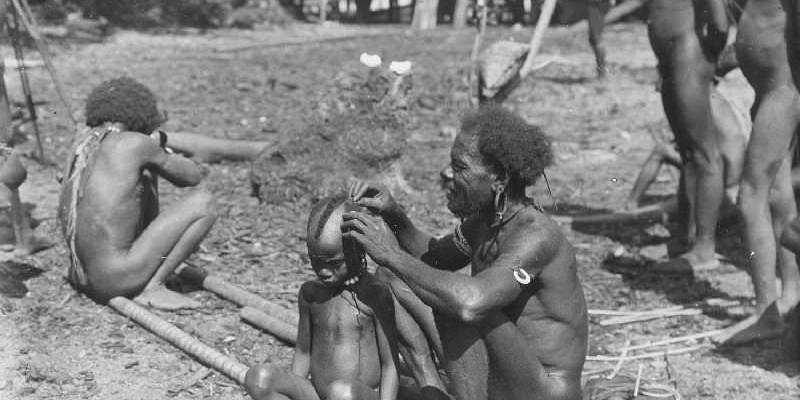 Indigenous family engaging in cultural grooming and bonding outdoors.