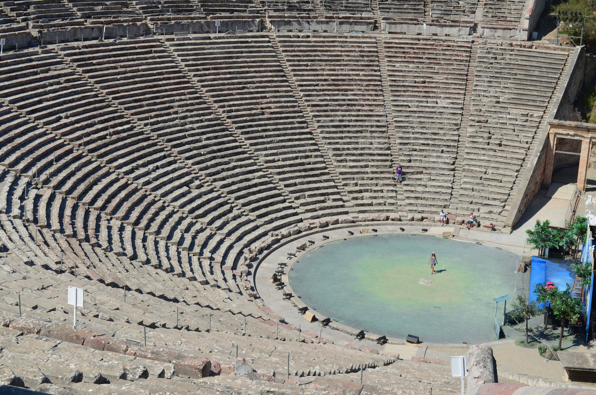 Ancient Greek theatre ruins with tiered seating and central stage area.
