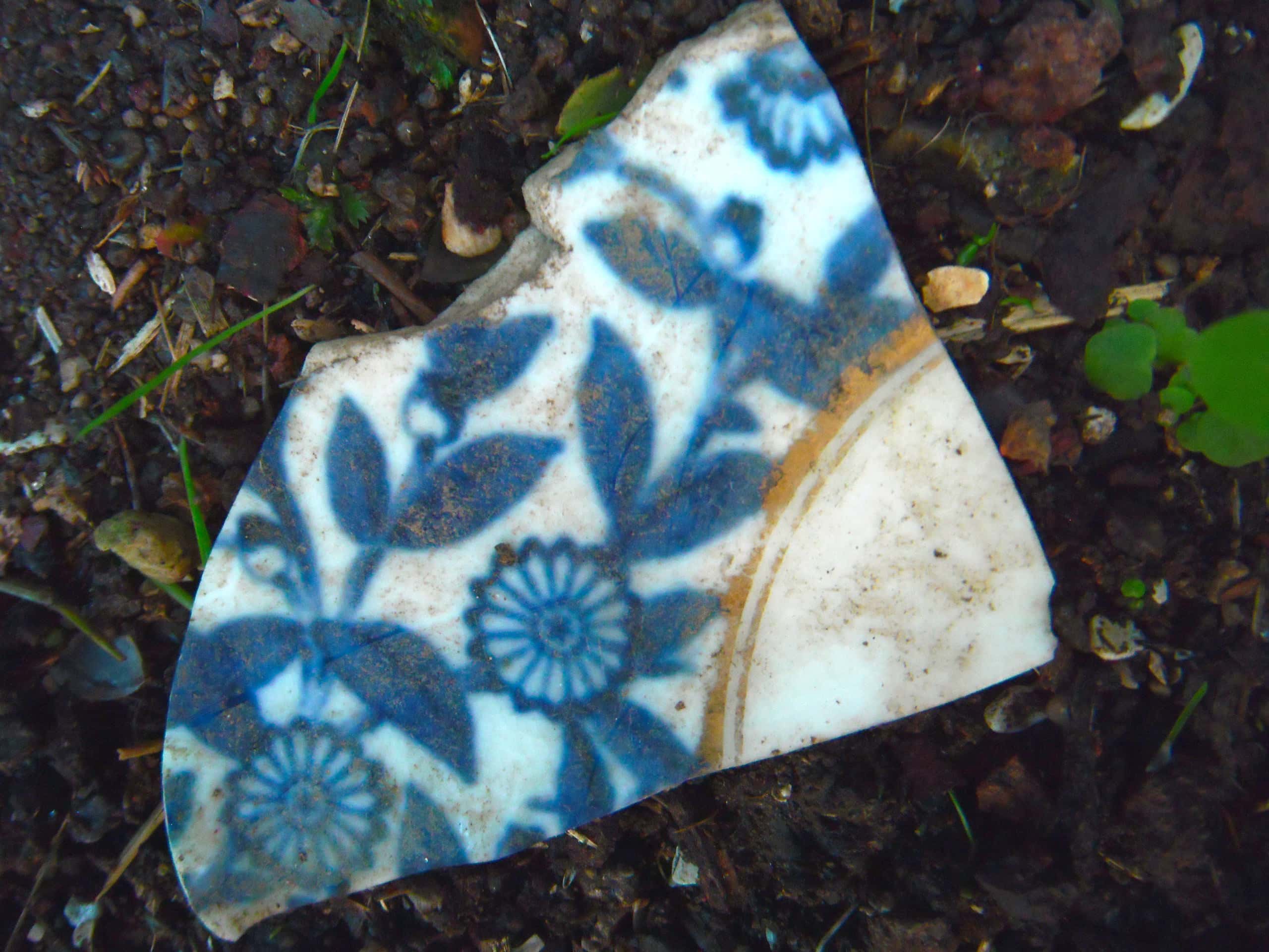 Blue and white ceramic shard with floral patterns, symbolizing tradition and craftsmanship.
