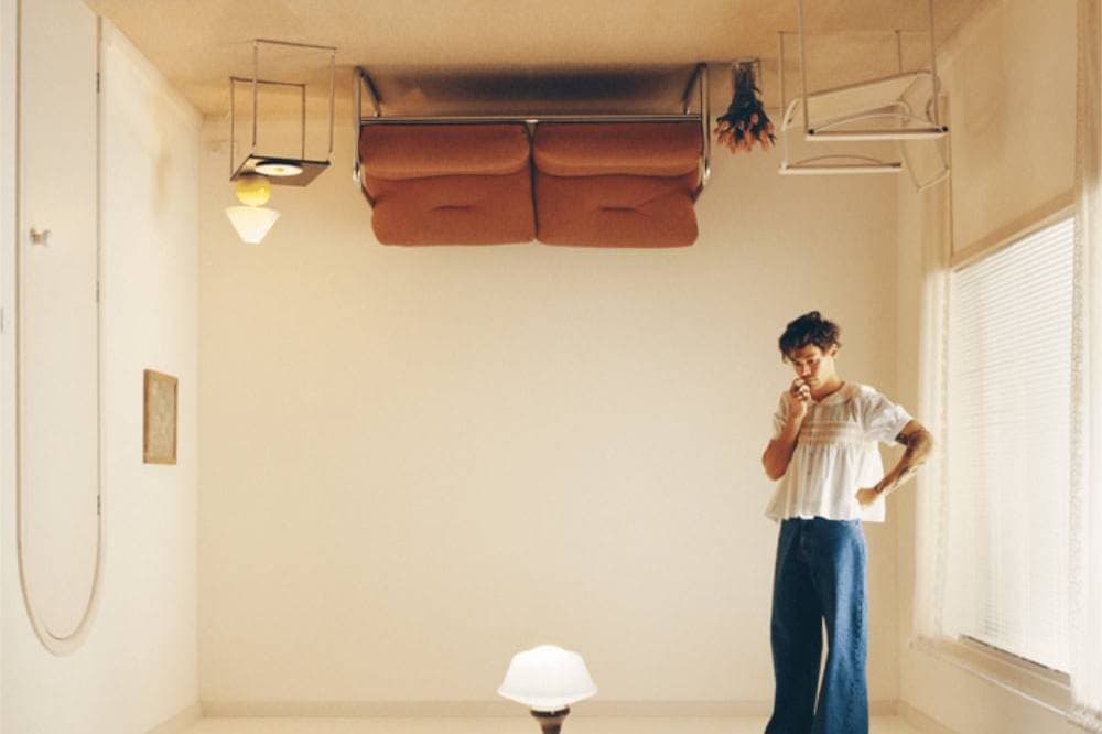 Upside-down furniture in a minimalist room with a woman pondering, creating a surreal, thought-provo.