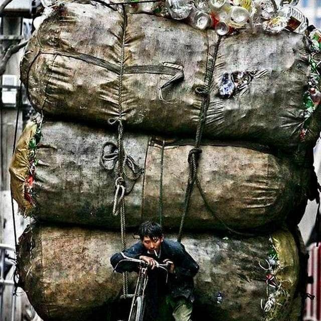 Garbage truck overloaded with trash and aluminum cans in an urban setting.