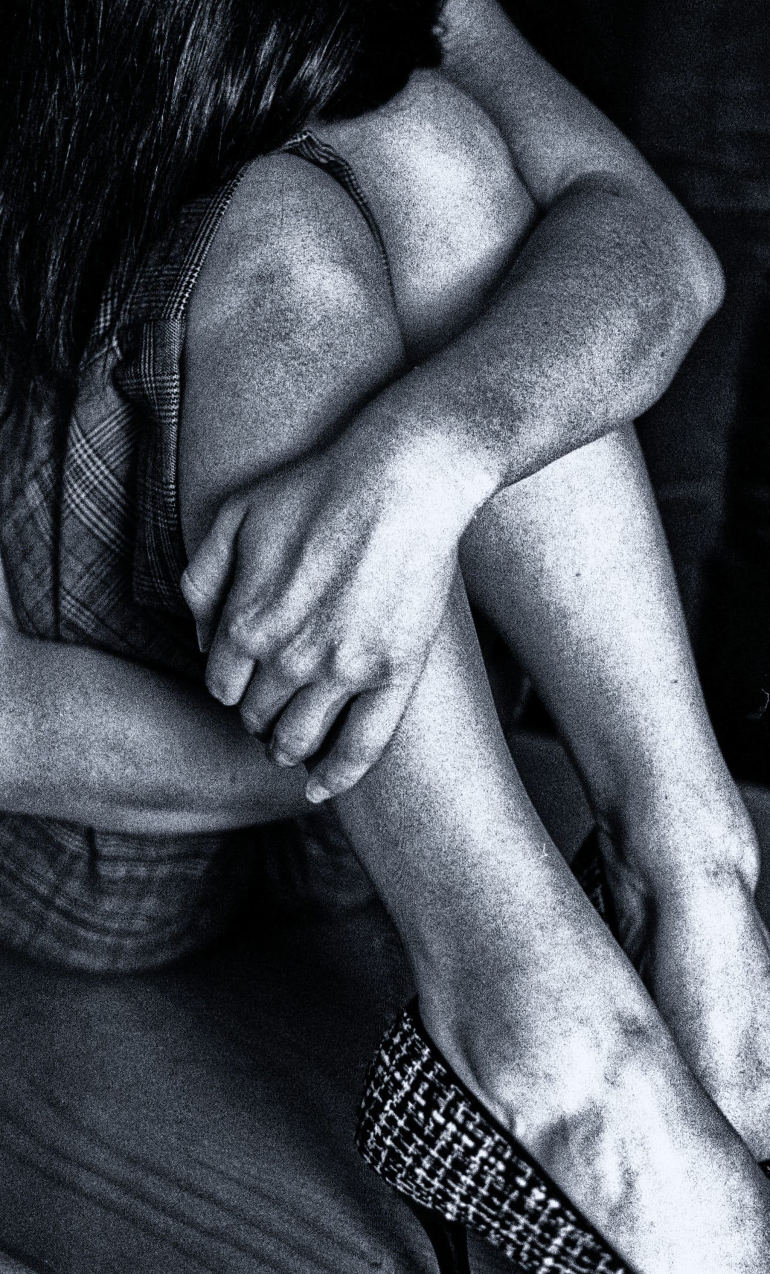 Emotional black-and-white photo of a person hugging their knees, symbolizing shame and vulnerability.