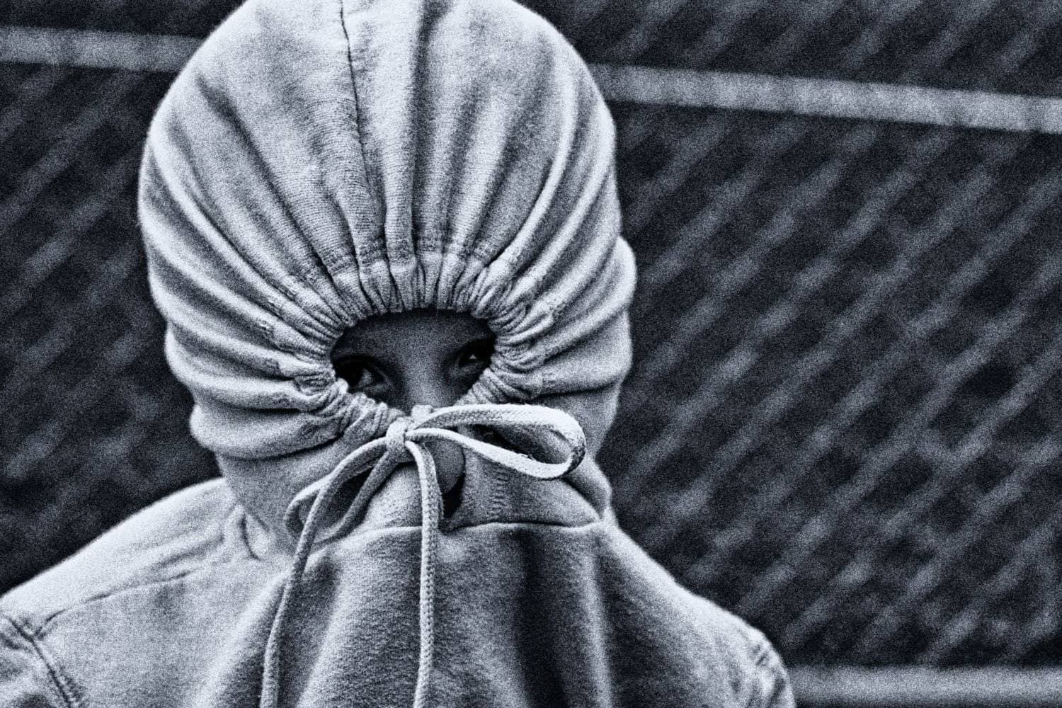 Person with hoodie covering face, symbolizing shame and concealment.