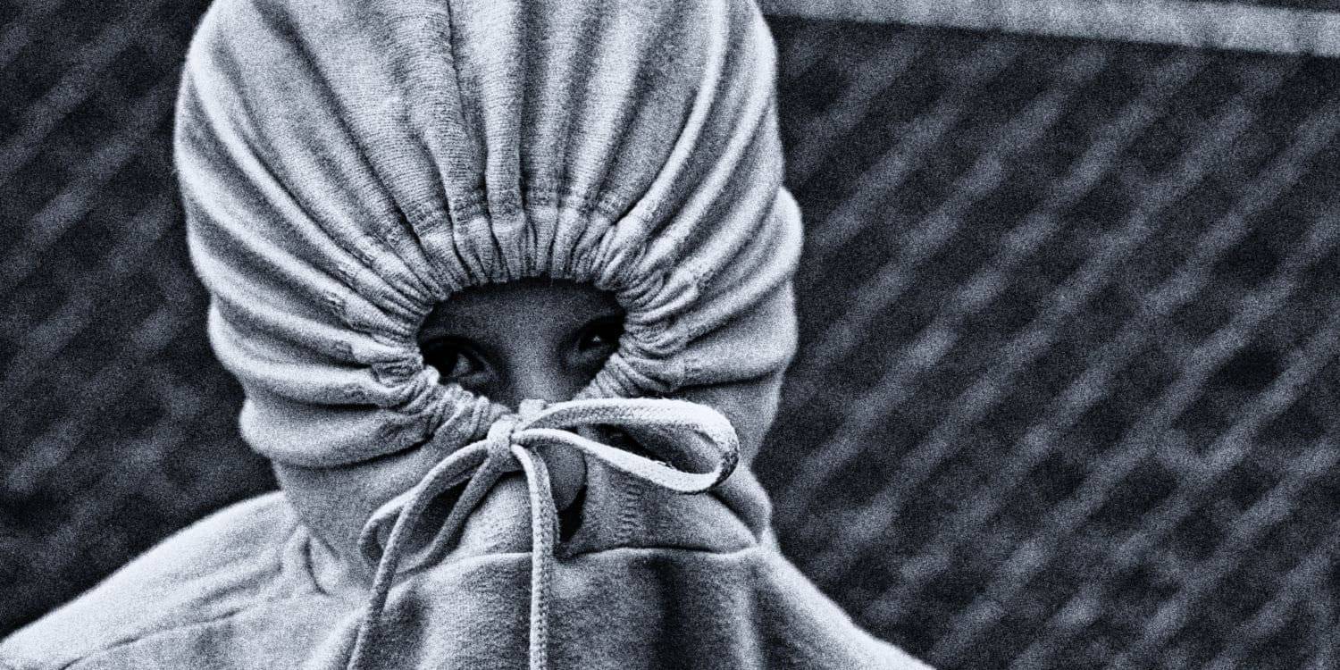 Person with hoodie covering face, symbolizing shame and concealment.