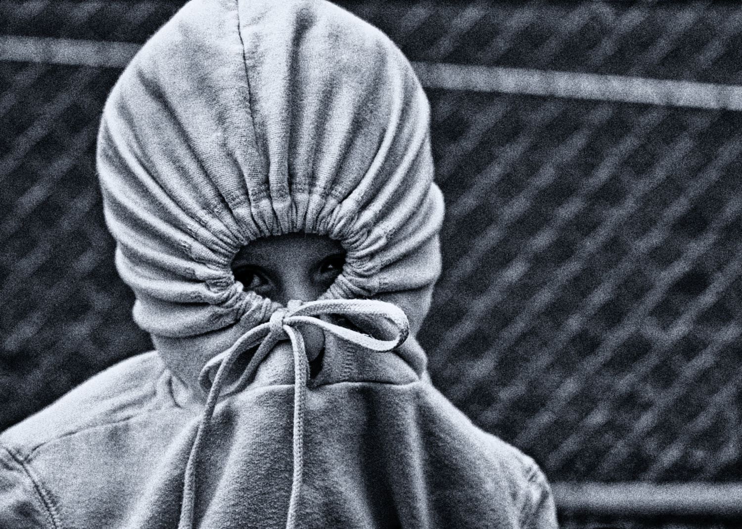 Person with hoodie covering face, symbolizing shame and concealment.