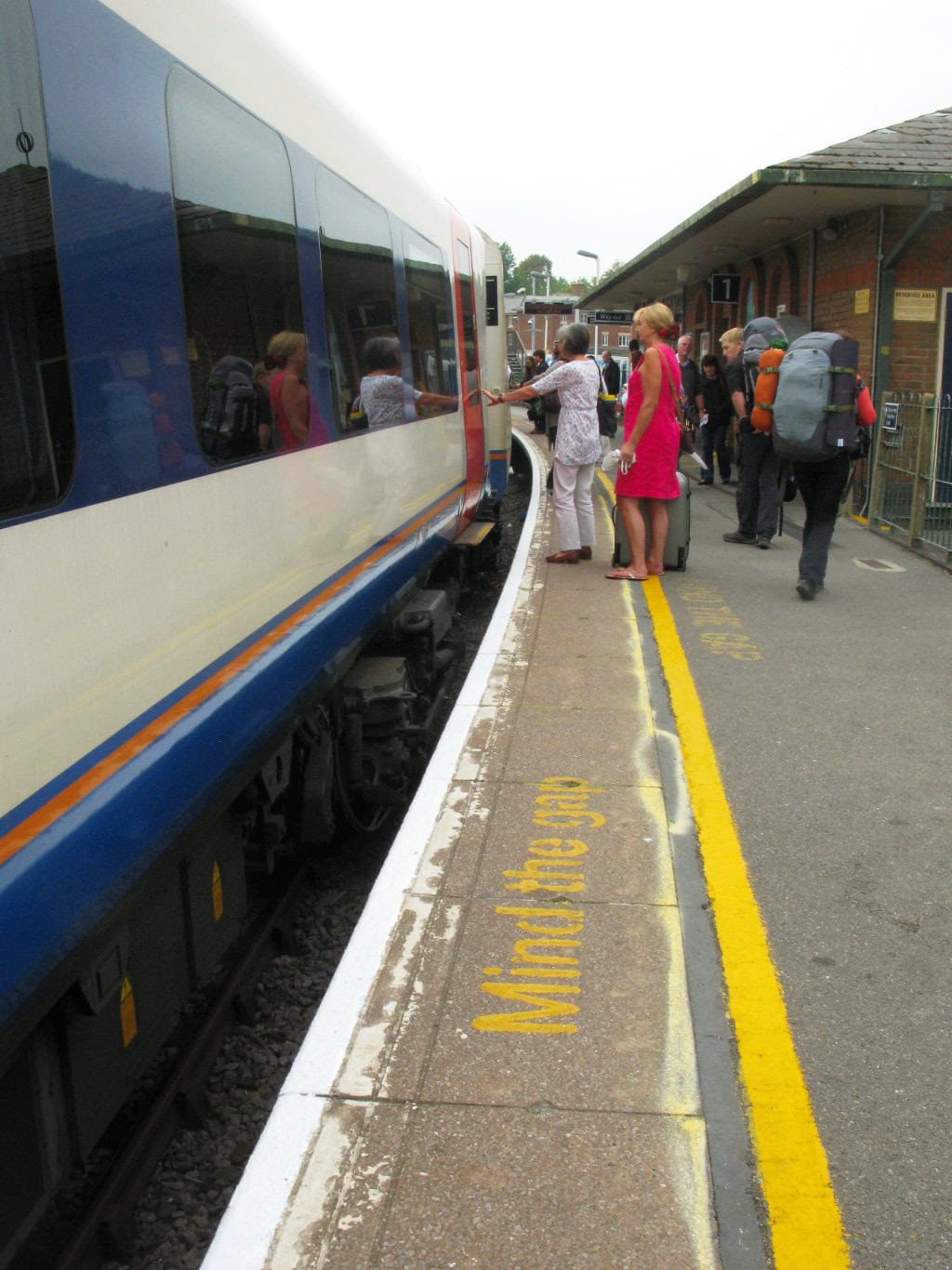 People boarding a train at a busy station platform.