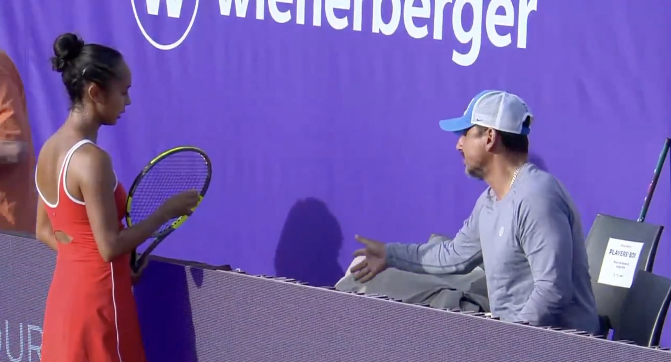Tennis player Leylah Fernandez and coach in discussion during match.