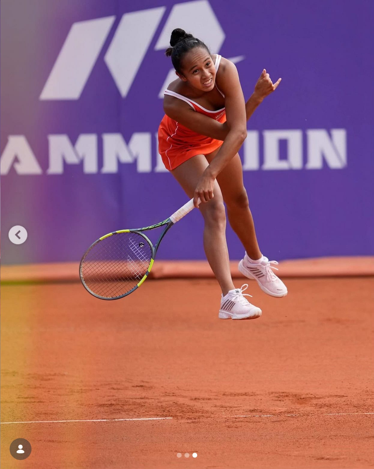 Young female tennis player celebrating on court with racket in hand.