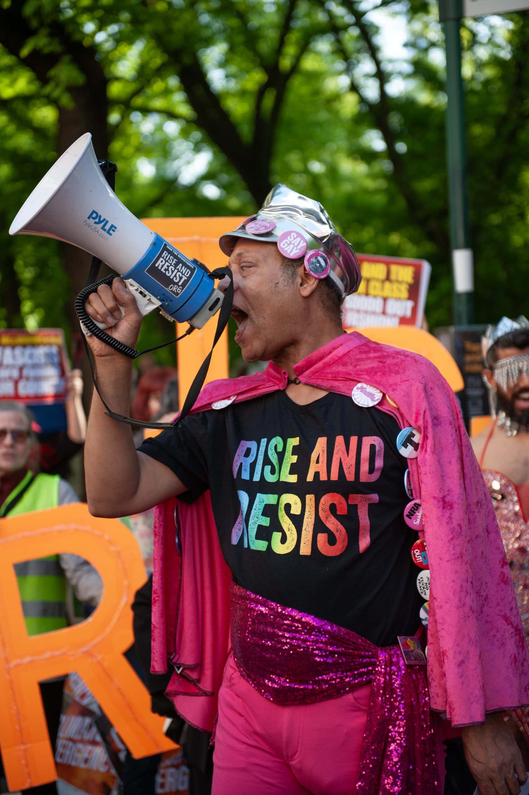 Empowered activist at pride parade using megaphone, wearing vibrant pink outfit and