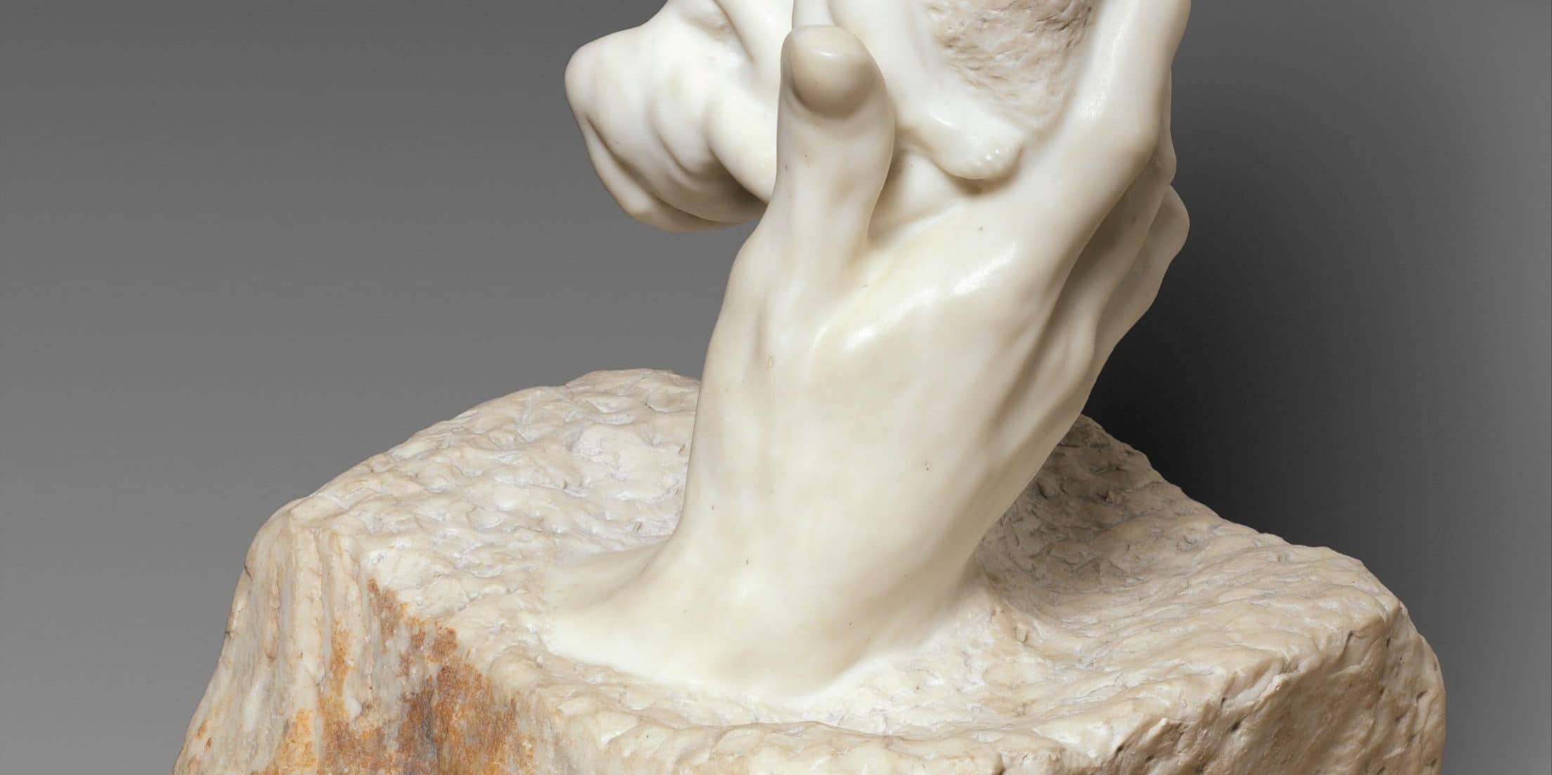 Stone hand holding a rock sculpture, symbolizing the birth of inhumanity.