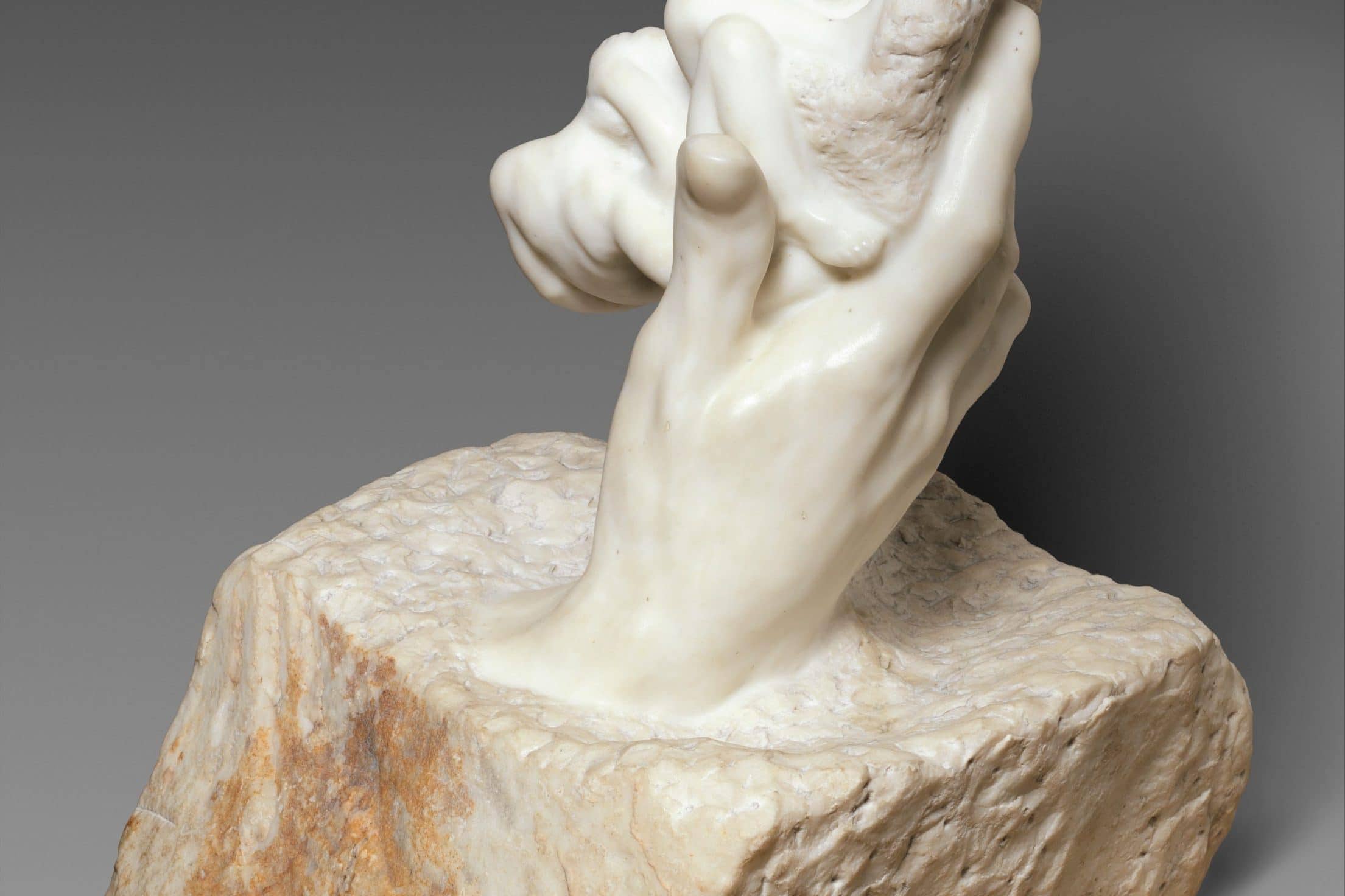 Stone hand holding a rock sculpture, symbolizing the birth of inhumanity.