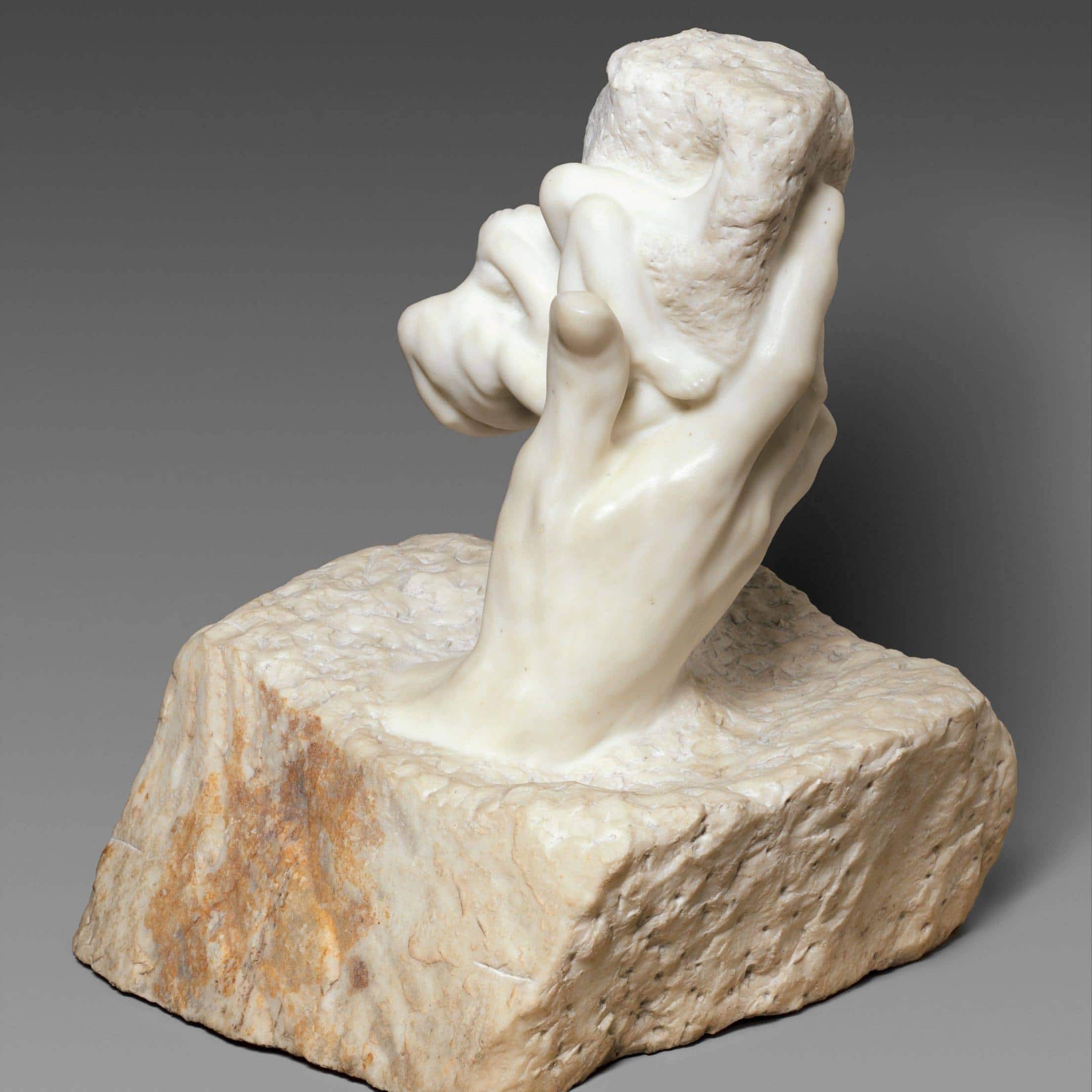 Stone hand holding a rock sculpture, symbolizing the birth of inhumanity.