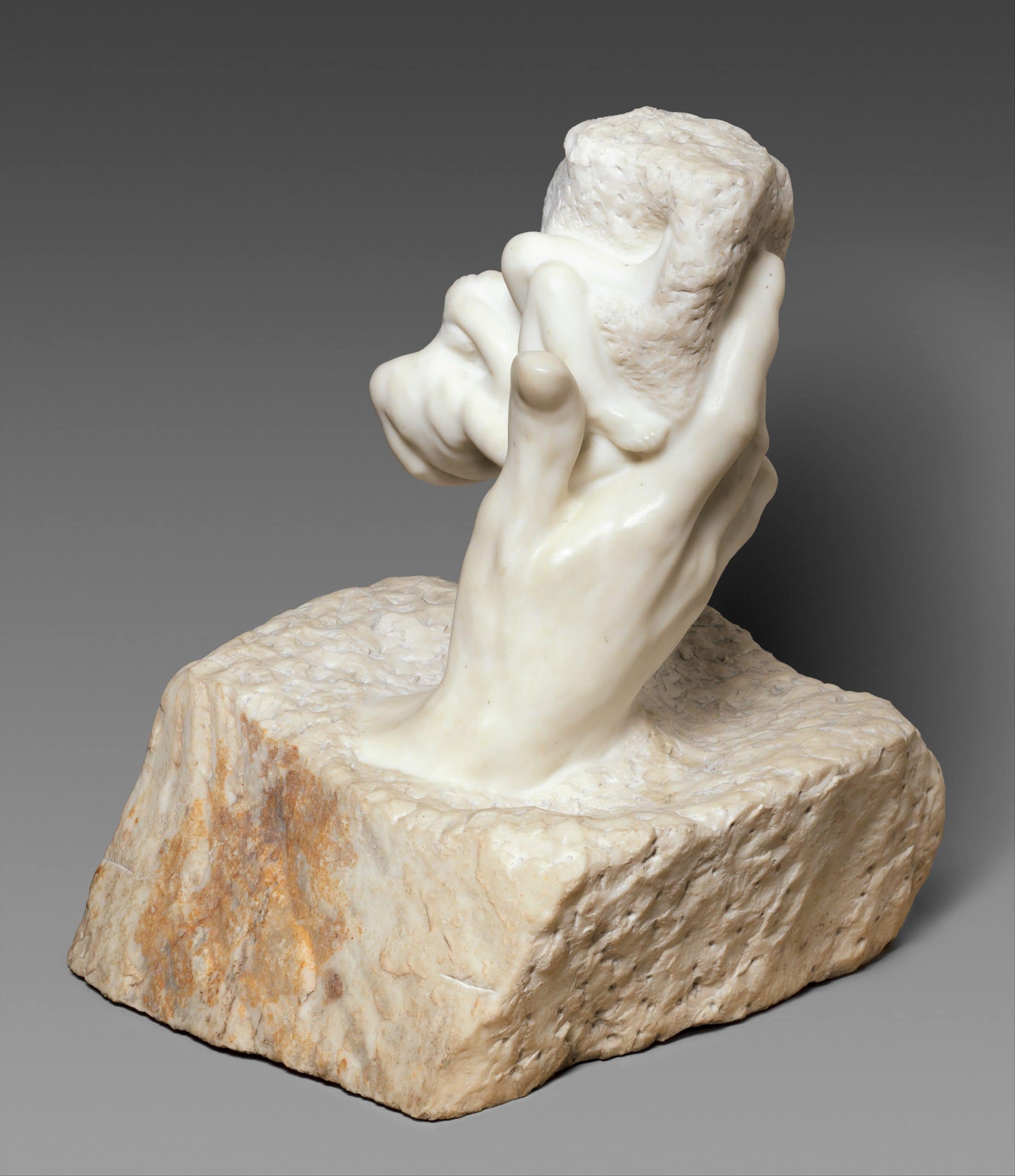Stone hand holding a rock sculpture, symbolizing the birth of inhumanity.