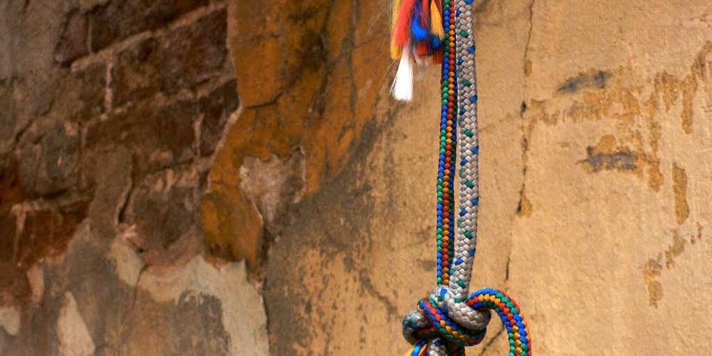 Vibrant beaded necklace hanging on a textured, rustic wall for cultural decor.