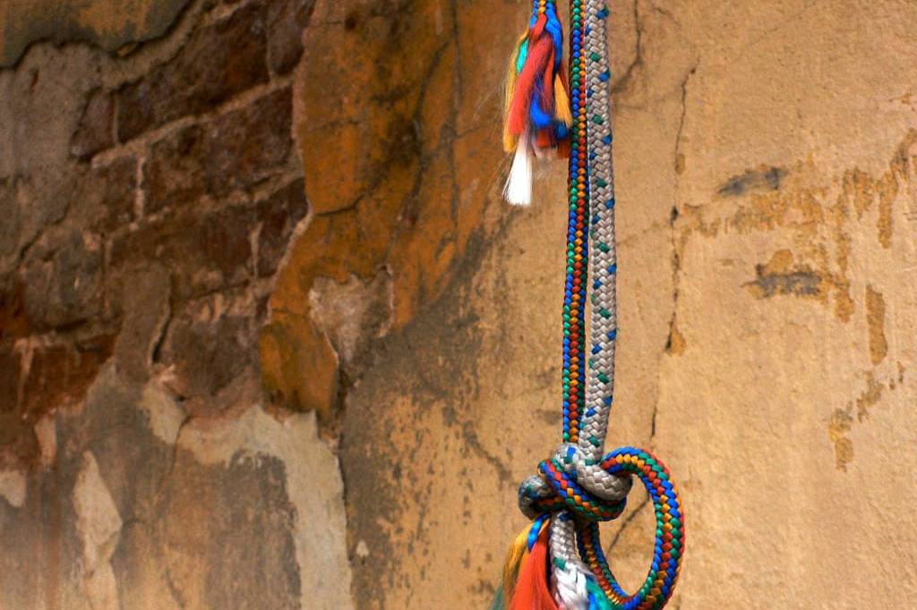 Vibrant beaded necklace hanging on a textured, rustic wall for cultural decor.