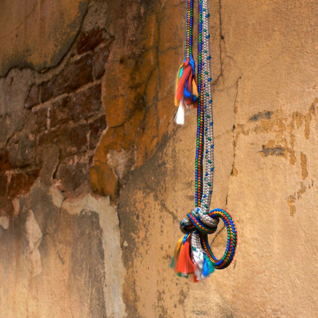 Vibrant beaded necklace hanging on a textured, rustic wall for cultural decor.