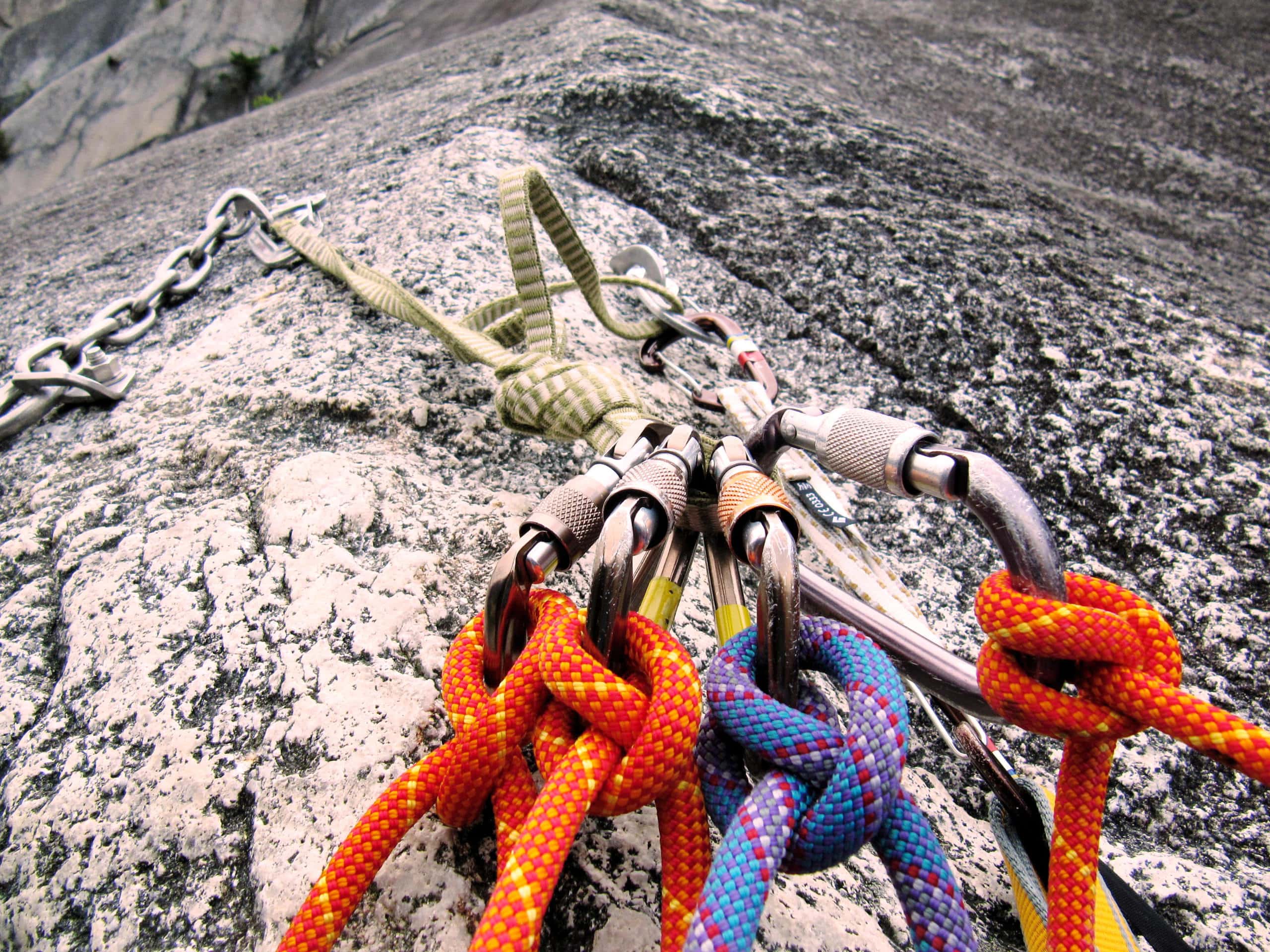 Climbing harness and carabiners attached to a rock face for safety.
