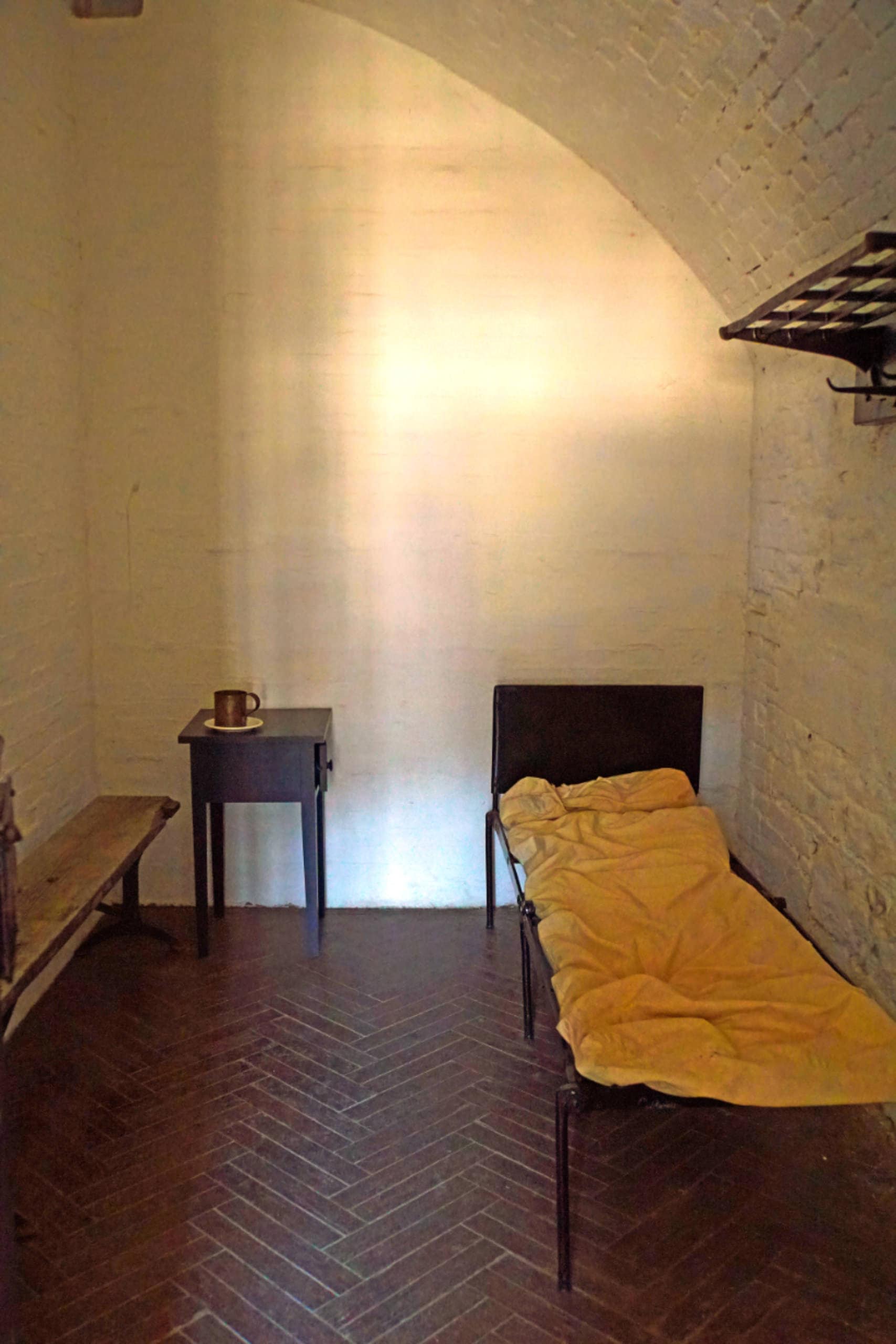 Simple bedroom with bed, side table, and exposed brick wall.