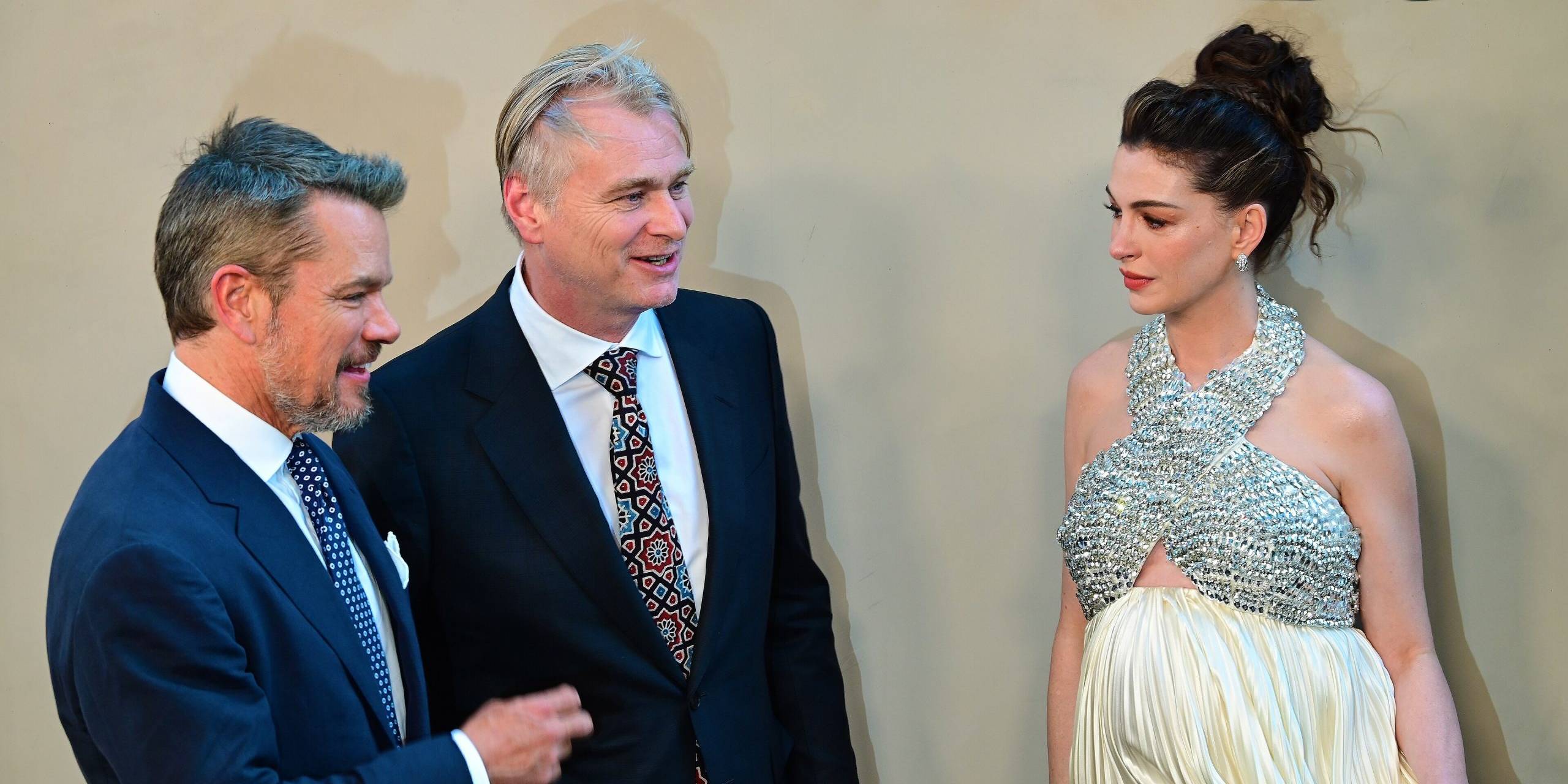 Three people in formal attire at The Odyssey event, engaging in conversation.
